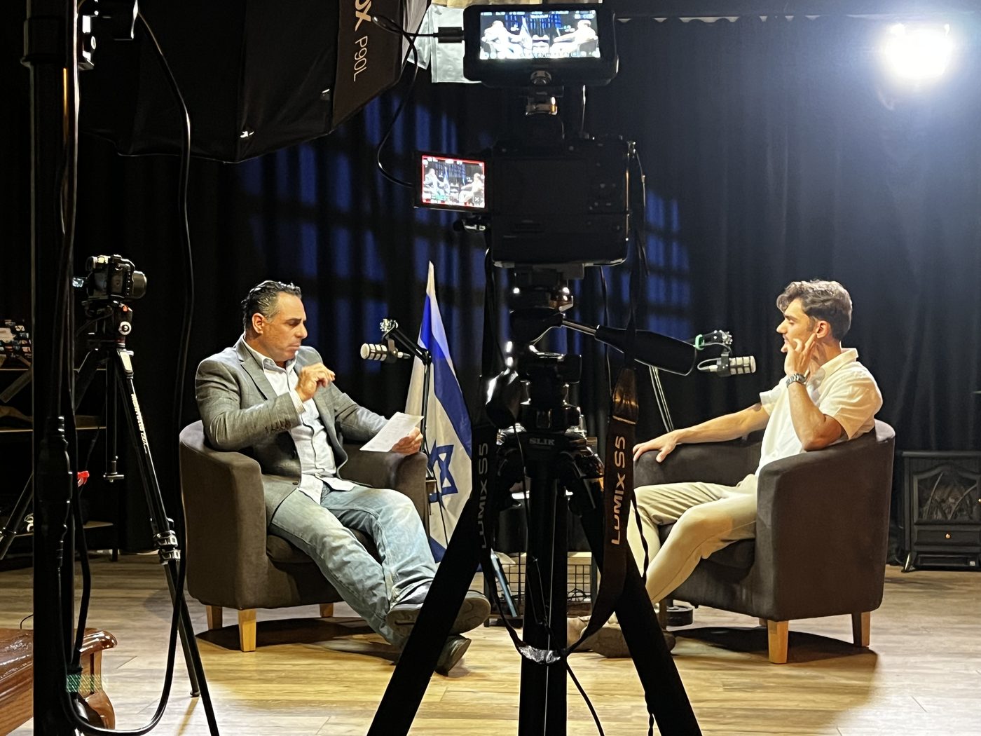 Interview at the GalilTV studio, Israeli flag in the background